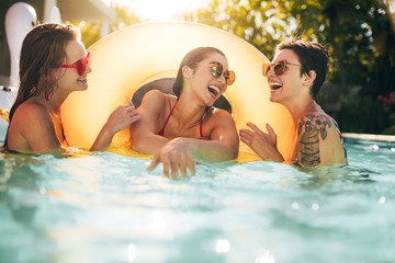 Friends laughing and enjoying in swimming pool - obrazy, fototapety, plakaty