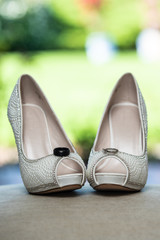 Peep toe high heel shoes of the bride holding the husband and wife wedding rings on top.