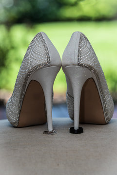 Stiletto high heel shoes of the bride holding the husband and wife wedding rings in place.