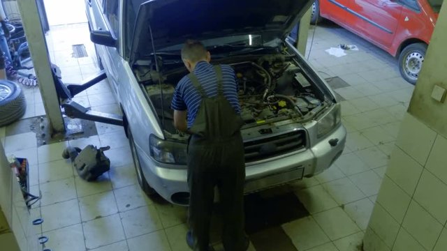 Top view of auto mechanic repairs the car at the service station