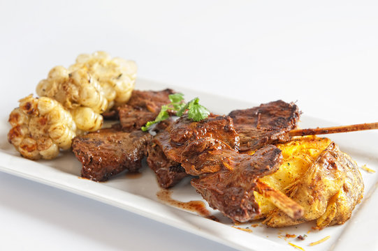 anticuchos, grilled skewered beef heart meat with boiled potato and white corn
