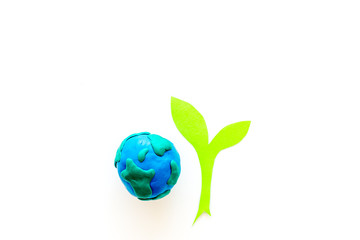 Planet, ecology. plastiline symbol of planet Earth globe and plant coutout on white background top view copy space