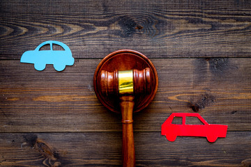 Car accident lawsuit concept. Two collided cars near judge gavel on dark wooden background top view...