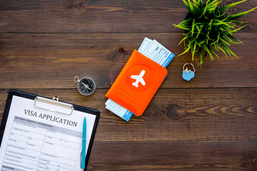 Prepare to trip. Do visa. Airplane tickets near passport cover with airplane silhouette, visa application form, compas on dark wooden background top view copy space © 9dreamstudio