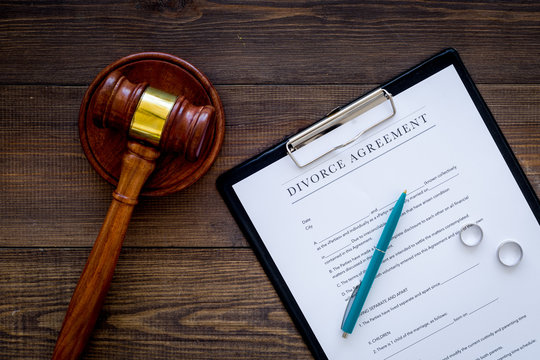Divorce court case. Divorce agreement near wedding rings and judge gavel on dark wooden background top view