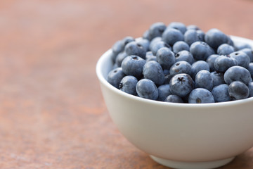 A bowl of freshly picked blueberries on a rustic table