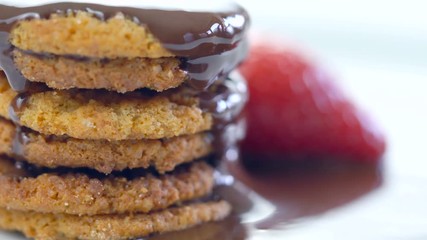 Chocolate sauce dripping over stack of cookies, macro closeup.