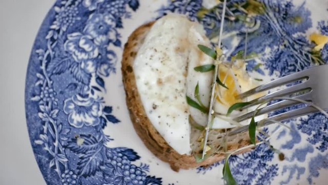 Taking a piece of sandwich bread with egg and sprouts on top