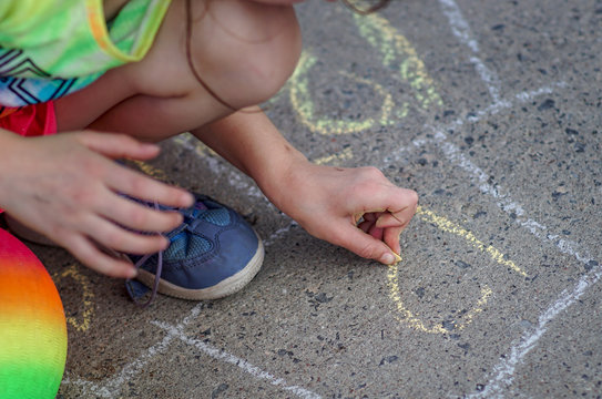 Child Drawing On Sidewalk With Chalk