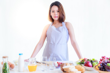 Portrait charming beautiful housewife: Attractive girl is pregnant. Pretty mother loves cooking and eating healthy foods. She has confident. She stands in a kitchen at house and preparing for cooking