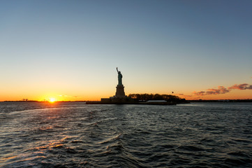 Fototapeta na wymiar Sunset view of Liberty Statue silhouette from Ellis Island Ferry Tour‎