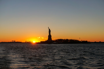 Sunset view of Liberty Statue silhouette from Ellis Island Ferry Tour‎