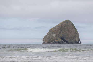 Rocky island in ocean. Right side location. Small waves. Overcast.