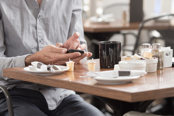 Fototapeta na wymiar A man using a smart phone while enjoying a cup of coffe in a cafe
