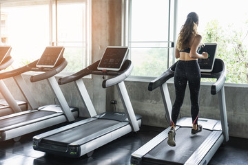 Cute young woman exercising on  treadmill at a gym.Active young woman running on treadmill. smile and funny emotion.