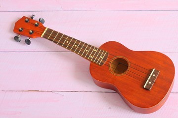A ukulele on the pink wood background.