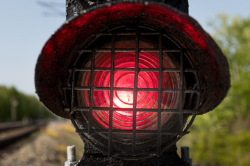 Old and dirty red shunting light at the railway, close-up. Blurred railroad and green tree at the...