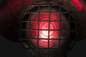 Old and dirty red shunting light at the railway isolated on a dark background, close-up.