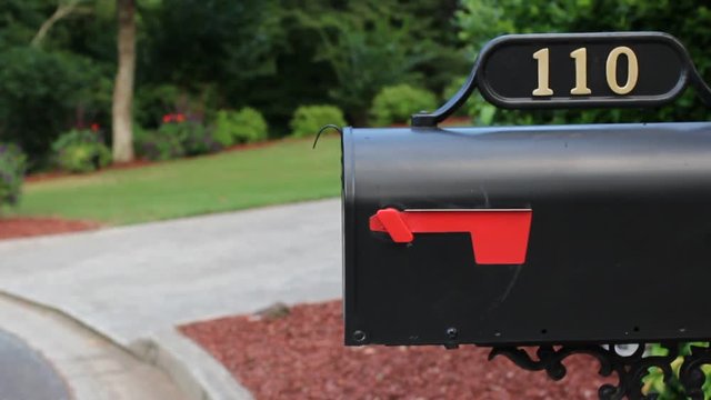 Man walking to mailbox, putting letters in it, closing it, putting up the flag, and walking away