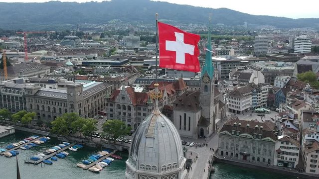 Aerial drone shot flying past the Swiss Flags on Grossmunster church in Z&uuml;rich, Switzerland