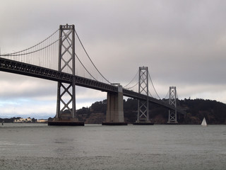 Fototapeta na wymiar Boat sail by the San Francisco side of Bay Bridge on a foggy day