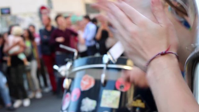 woman applauding the beat with blurry drummer and audience in the background