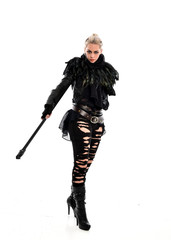 Fototapeta premium full length portrait of blonde girl wearing black gothic outfit, holding a staff. standing pose, isolated on white studio background.