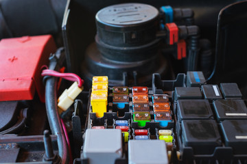 Close up many colorful electrical automotive car fuse inserted in fuse box in car engine.