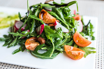 Healthy vegetable summer salad, fresh vegetables and dressing with grilled cheese flambe arranged on plate dinner table