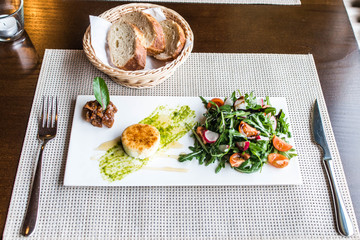 Healthy vegetable summer salad, fresh vegetables and dressing with grilled cheese flambe arranged on plate dinner table