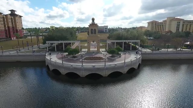 This shot revealings a park plaza in a high residential area. As the drone pulls away, it passes over the lake that the park surrounds, while revealing more of the surrounding area.