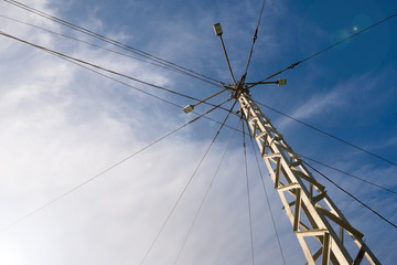 Fototapeta premium High voltage electricity truss metal pole with complex wiring, led street lamps with blue sky at the background.