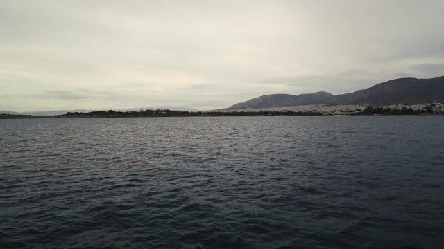 Flying over the sea on a cloudy day. Small island on the horizon.