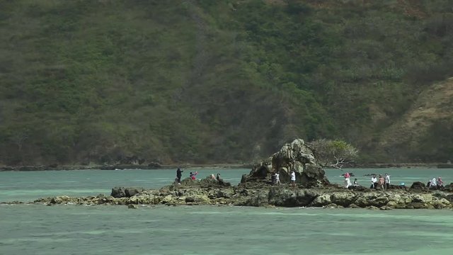 People having fun on rock at Kuta Beach Lombok