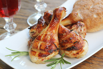 Grilled chicken legs with rosemary served on white plate. Dinner background