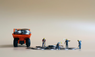 Miniature workers loading a truck with coins. A concept of the relationship between labor and...