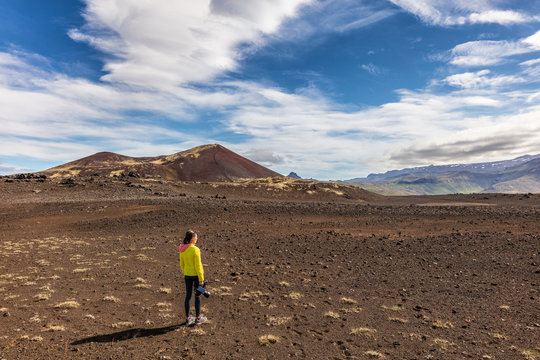 Hiking in Iceland - Adventure travel. Videographer girl tourist on wanderlust walk filming video with camera. Hero landscape shot of desert nature.