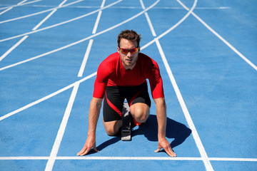 Runner athlete starting running at start of run track on blue running tracks at outdoor athletics...