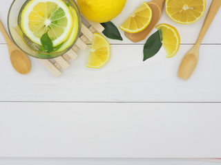 Fresh lemon in water and lemon slice on white wood background