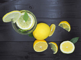Fresh lemon juice in small bowl and lemon slice on dark wood background