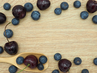 Fresh cherry and blueberry with spoon on wooden background. Healthy food and diet.