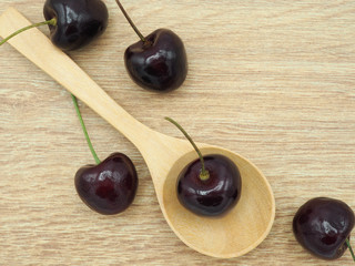 Fresh cherry with spoon on wooden background. Healthy food and diet.