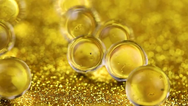 Crystal Gel water balls on gold glitter texture rotation. Close up macro footage.