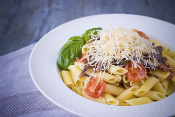 Pasta with cherry, tomato-basil sauce and parmesan on white plate.