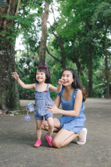 Portrait of little girl hugging her mom with nature and sunlight, family concept