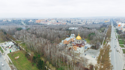 Aerial view of the autumn park, church and roads against the background of multi-storey houses. Ukraine Ternopil