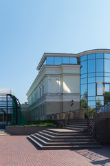 The facade of the building with wide steps of the staircase leading to the entrance with mirrored glass.