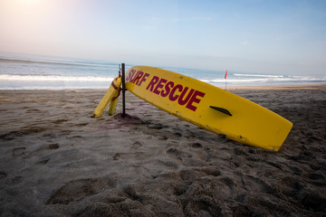 Yellow surfboard on the sand with the word rescue in red