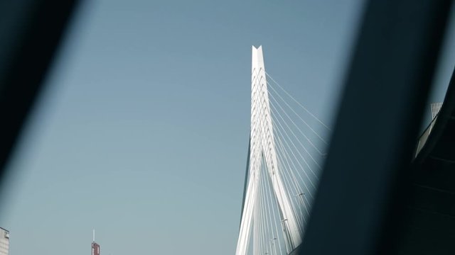 Cinematic shot from behind a stairs railing, revealing the Erasmus bridge of Rotterdam.