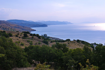 A calm sea bay with a coastal strip of stony hills reaching the water itself.
